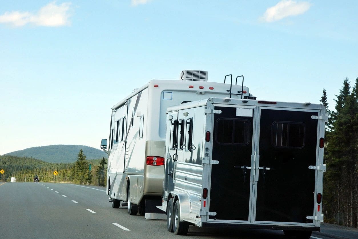 A white and black trailer is parked on the side of the road.