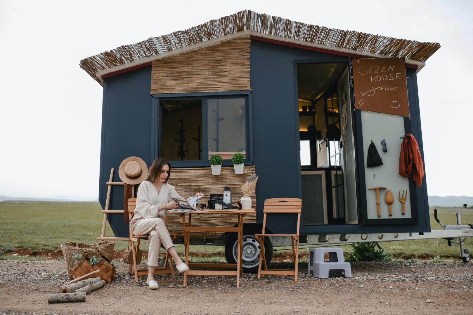 A woman sitting at the table outside of her tiny house.